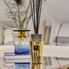 Baobab Collection TOTEM LES EXCLUSIVES AURUM diffuser with black sticks and gold finish on a stylish table.