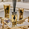 Baobab Collection TOTEM AURUM fragrance diffuser with black sticks on a reflective coffee table.
