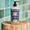 Baobab Collection Manhattan body and hand lotion in ornate glass bottle on wooden stump.